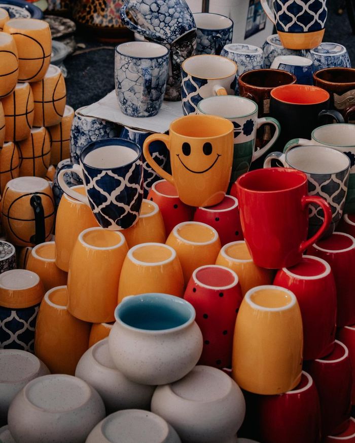 Vibrant arrangement of ceramic mugs displayed at a market highlighting diverse patterns and colors.