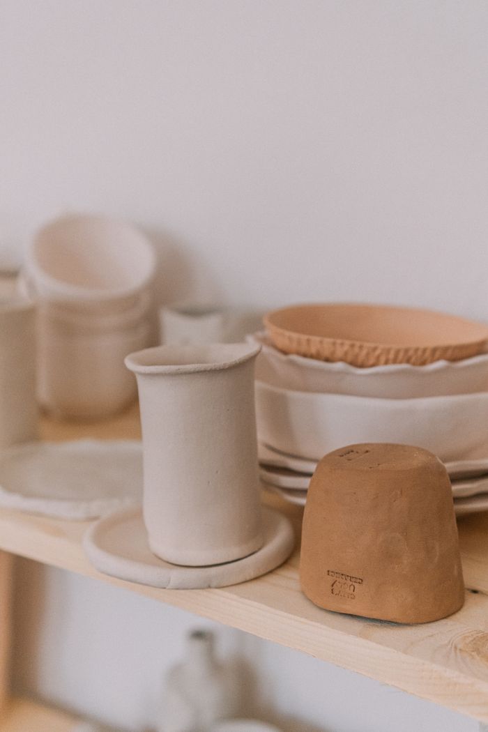 services-04 A collection of handmade ceramic dishes arranged on a rustic wooden shelf.