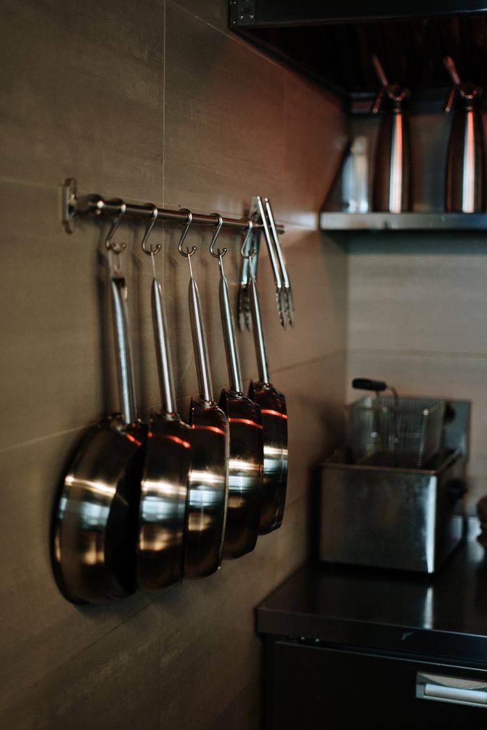 services-02 Elegant arrangement of stainless steel pans hanging in a contemporary kitchen setting.