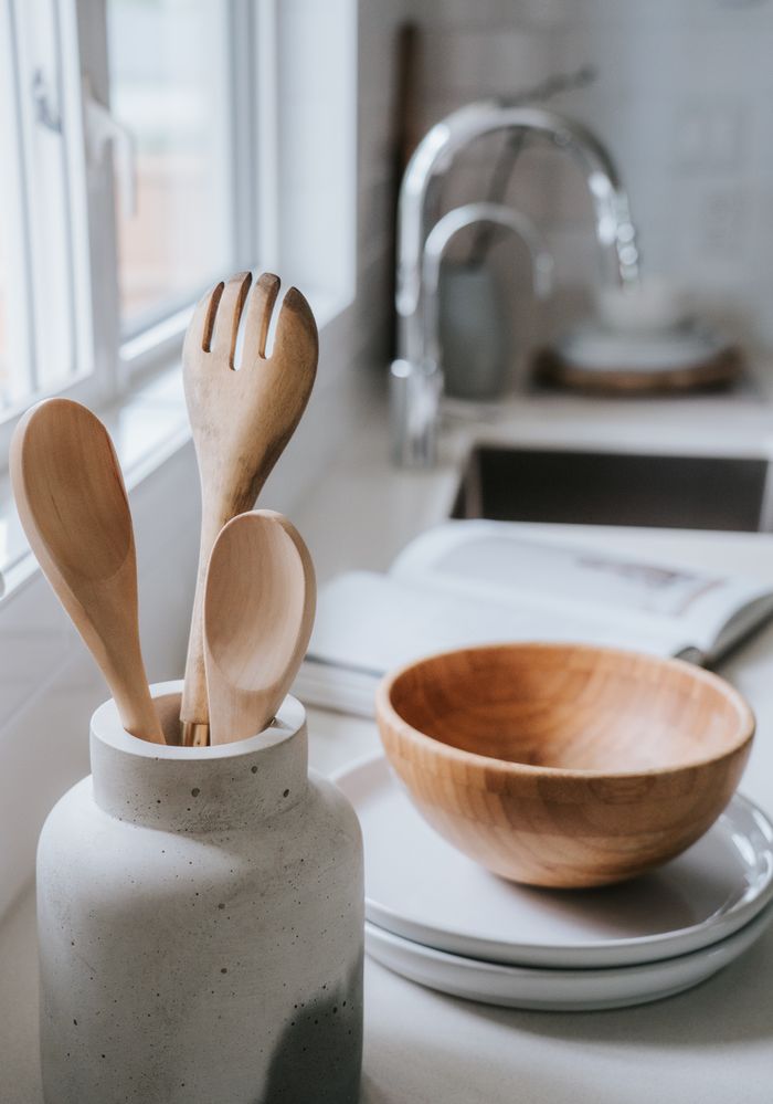services-03 A serene minimalist kitchen scene showcasing wooden utensils and a bowl on a bright countertop.