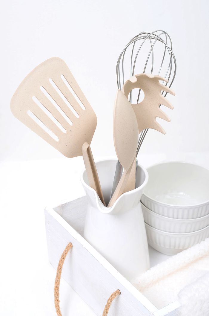 Neutral-toned kitchen utensils in a white holder, perfect for modern kitchens.